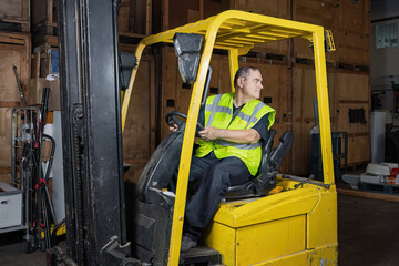 Warehouse worker reversing forklift truck while looking behind © Tosh Lubek