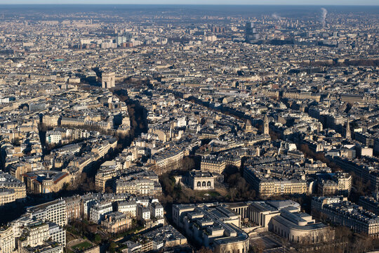 Aerial view of Paris showing dense urban architecture historic streets and iconic landmarks under clear daylight highlighting city scale travel cultur, with Arc de Triomphe monumente and European