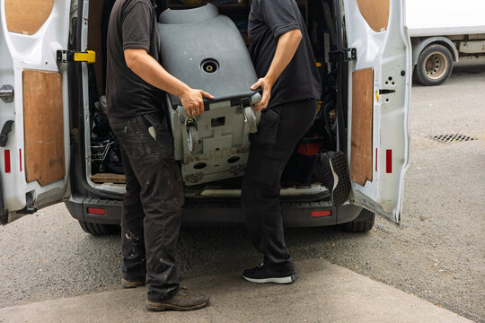 Two workers unloading industrial carpet cleaning machine from service van