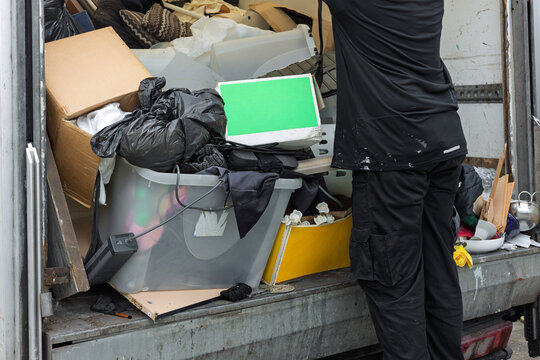 Worker unloading mixed waste and household items from van or truck