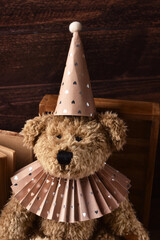 Portrait of vintage style teddy bear wearing paper ruff collar and a cap