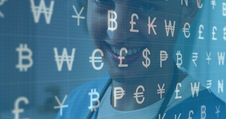 Smiling doctor in blue scrubs with stethoscope viewing screen in clinic showing currency symbols