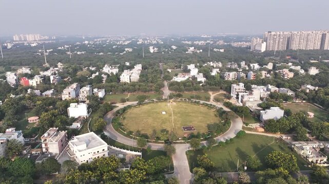 Aerial view of a massive Indian national flag soaring above a circular park in Greater Noida, surrounded by leafy residential sectors&mdash;symbolizing pride, openness, and planned urban living.