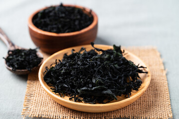 Dried wakame seaweed on a wooden plate with spoon and bowl, Healthy Asian food ingredient © nungning20