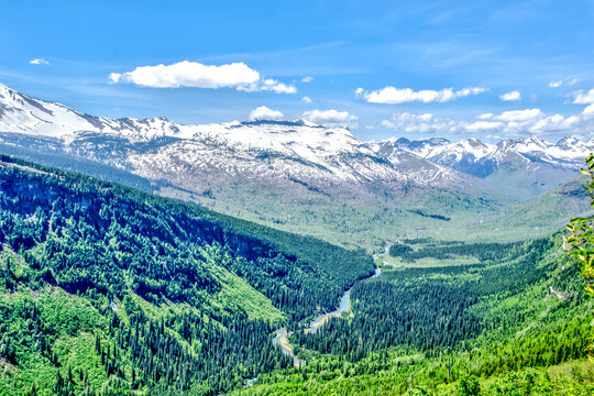 A mountain range with snow on the peaks and a river running through the valley