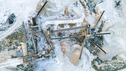 Top down aerial view of a complex industrial conveyor system radiating from a central point at a snowy gravel production site © Buğra Kaan Ersoy