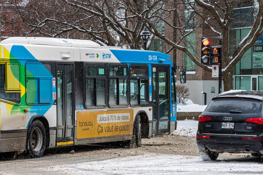 Canada, Montreal, 25 December 2025 : Bus and car stopped at snowy intersection traffic light red