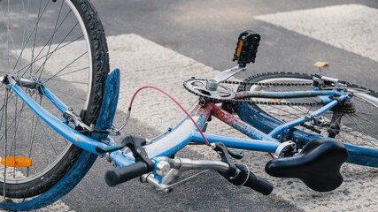 Blue bicycle lying on a pedestrian crosswalk after a road traffic accident.