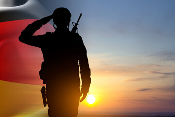 Naklejka premium Silhouette of saluting soldier with Germany flag against the sunset. National Holidays concept