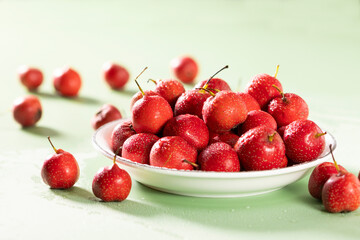 Fresh red hawthorn berries in a white ceramic bowl on a light green and grey background