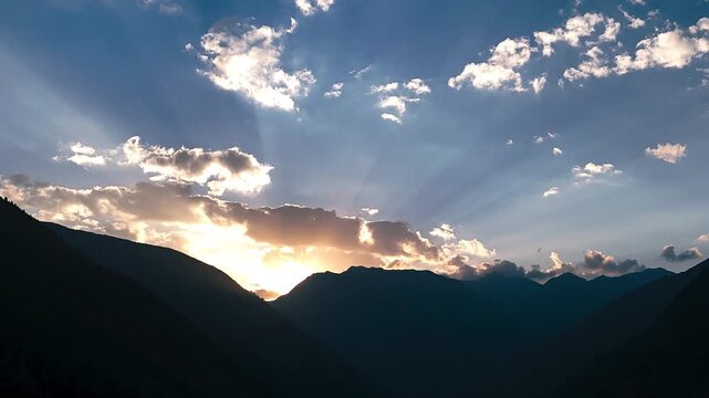 Drone Hyperlapse Sunset, Aerial forward motion through dark mountain valley with dramatic sunbeams shooting from behind the silhouetted moutains
