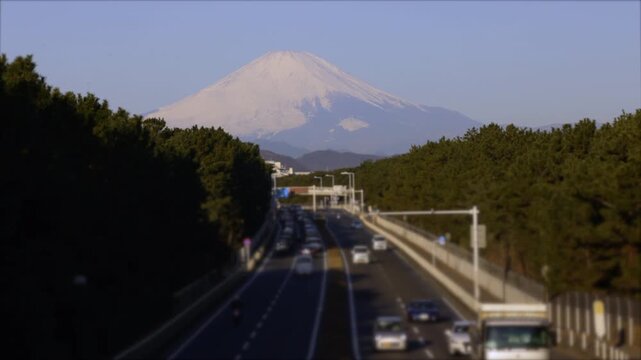 4K 60p wide angle view of morning traffic on Route 134 in Chigasaki, Kanagawa, with a majestic snow-capped Mt. Fuji visible in the distance. Cinematic landscape featuring busy commuter cars, morning s