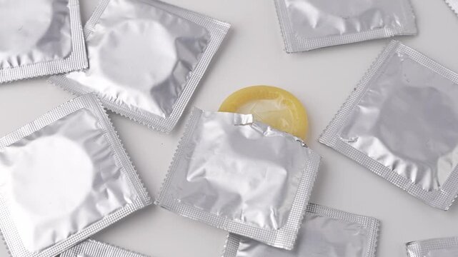 Showing packets of silver colored condoms on a white background.