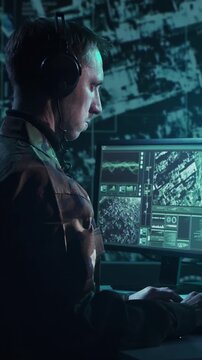 Soldier in a dimly lit military control room, intensely focused on multiple computer screens displaying crucial operational drone data.