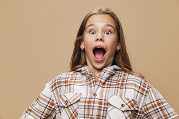 Girl with long hair wearing plaid shirt showing surprised expression with wide open mouth and...