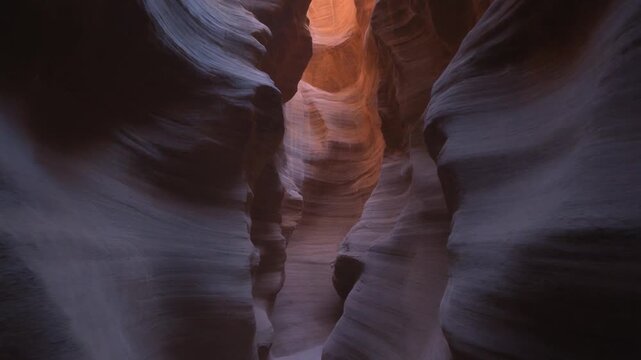 Walking through a narrow slot canyon with light at the end.