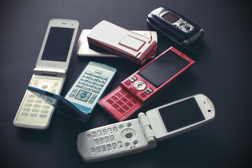 黒い背景に置いたひと昔前のガラケイの携帯電話