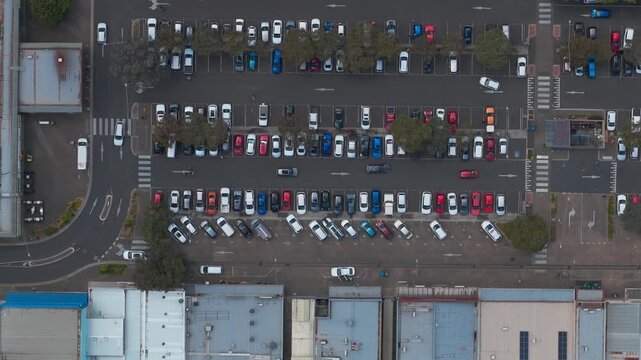 Aerial footage captures the bustling Boronia Melbourne carparks, showcasing a pattern of parked cars in vivid colors, under soft dusk lighting. The wide shot highlights urban organization.