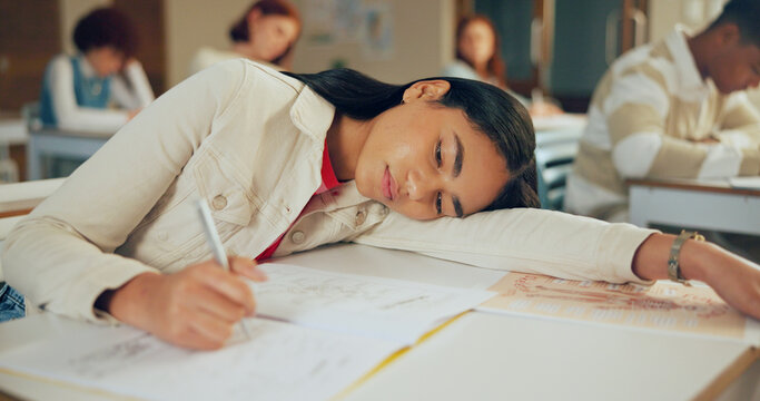 Tired, education and student in classroom with test, exam or assignment with fatigue or burnout. Writing, learning and girl teenager in lesson with exhaustion for studying with quiz at school.