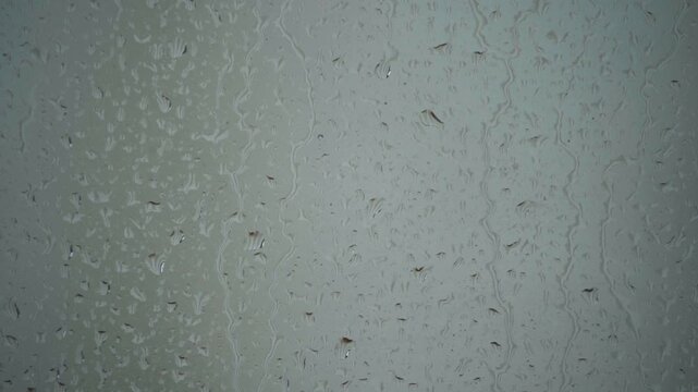 Raindrops on glass texture, Rainy window abstract background, Water droplets pattern surface, Monsoon rain glass backdrop, Wet glass minimal texture stock video. 