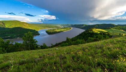 Panoramic view of a meandering river, hills, and meadow