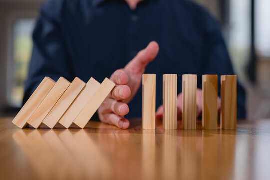 Hand stopping collapsing wood sticks dominos between two side of groups, Risk management Conflict solution concept