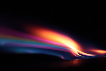 A vibrant, flowing wave of colorful light against a dark background, creating an ethereal and dynamic visual effect.