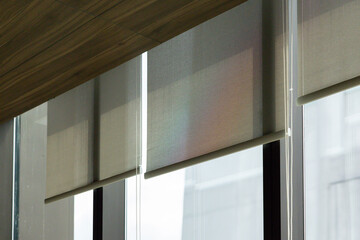 The window blinds are white and have a shiny, reflective surface. white rolling curtain in office.