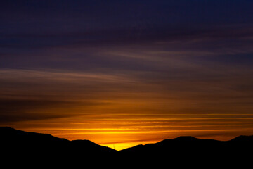 Afterglow washes the sky in violet and amber bands above quiet ridges forming a wide peaceful panorama that evokes calm evening moods and open space for travel wellness mindfulness and nature themes