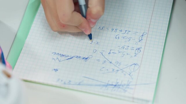 student writing blue pen on graph, closeup hand sketching equations and diagrams, notebook margin, scattered eraser bits, soft lamp glow, focused mood, quiet study session, exam preparation