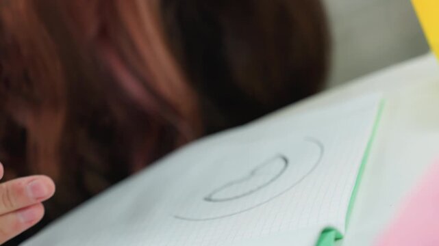 student tracing spiral with stencil pencil, closeup hands working on grid notebook, turquoise template used for accurate circles, steady strokes and precise alignment, calm study atmosphere, homework