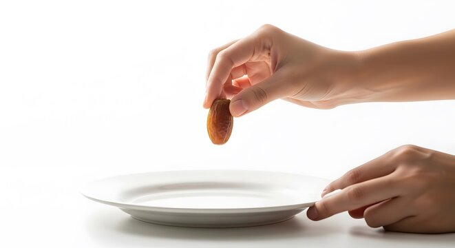 Ramadan Iftar & Suhoor Moments. A hand holding a dates over an empty white plate on a table
