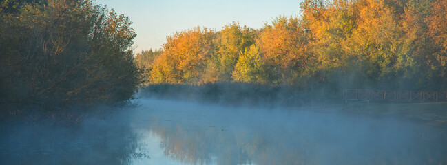Foggy lake landscape in the rays of the morning sun.