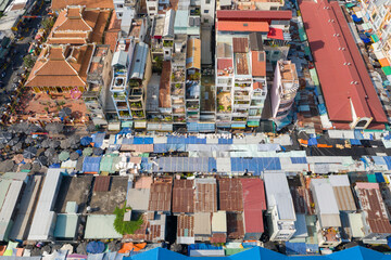 Aerial view of colorful striped market canopies and narrow urban buildings in central Chau Doc, Vietnam. The image highlights a dense cityscape, traditional tiled roofs, and the vibrant patterns of