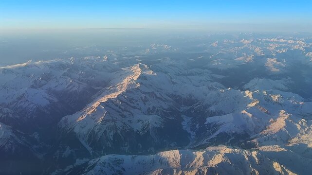 Immersive POV flying at sunrise over the Swiss Alps Range with the snow-covered peaks illuminated by the soft sunlight.