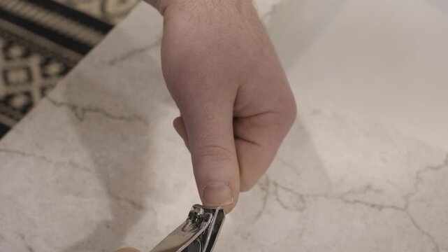 Trimming a long thumbnail with clippers.