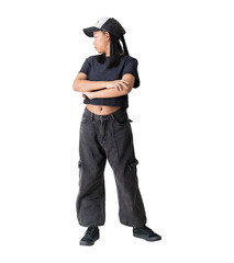 Stylish young girl wearing casual streetwear and a cap stands with her arms crossed while looking...