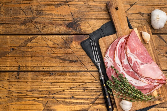Traditional German schinken meat served with thyme and garlic on aged wood ideal for culinary photography.