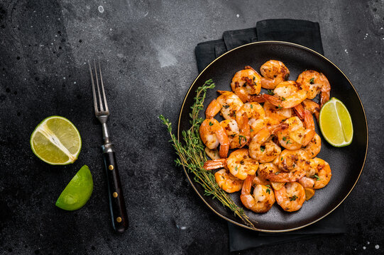 Grilled spicy Shrimps Prawns with garlic and lime in a plate. Black background. Top view