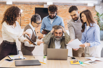 Overwhelmed senior businessman feeling stressed at work, surrounded by demanding colleagues...