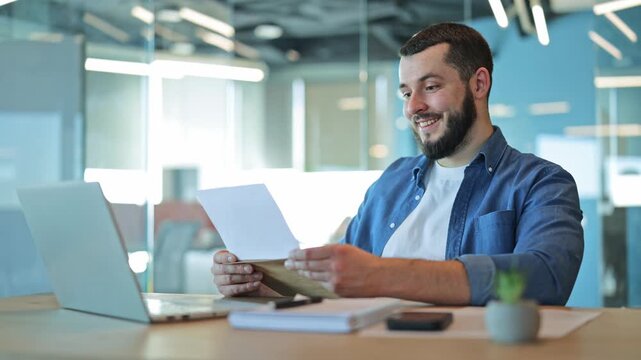 Adult at office desk opens mail. Greeted with positive news, reflecting happiness and satisfaction. Evokes feelings of success and good fortune within corporate environment.