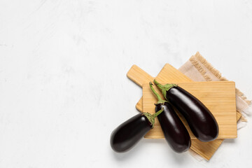 Composition with fresh eggplants, wooden cutting boards and napkin on white background