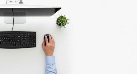 Overhead view of a person using a computer mouse on a desk with a keyboard and a small plant