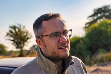 close-up Profile portrait of a smiling man with a beard wearing glasses outdoors © poco_bw