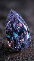 Faceted teardrop-cut purple gemstone on textured surface