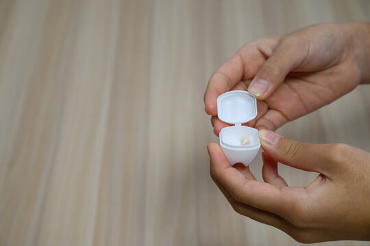 Child holding a small white case containing a lost baby tooth
