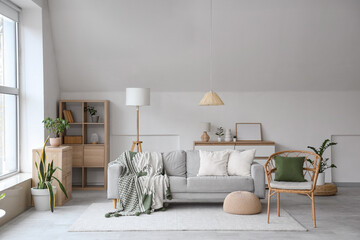 Interior of light living room with grey sofa, armchair and lamps