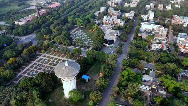 High-angle aerial of a Jaypee Greens tranquil urban park and lake, with sculpted shorelines, walking tracks, and fountains highlighting sustainable city planning and open spaces.
