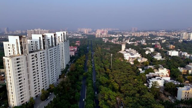 Drone footage over Swarn Nagri Road highlights high-rise apartments, dense greenery along the median, and long straight roads defining the modern residential landscape of Greater Noida.