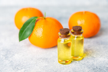 Tangerine essential oil on a wooden table. Bottles of citrus essential oil and sliced ​​fruits. Fragrant tangerine oil with tangerines. Cosmetic oil for spa treatments. Aromatherapy concept.